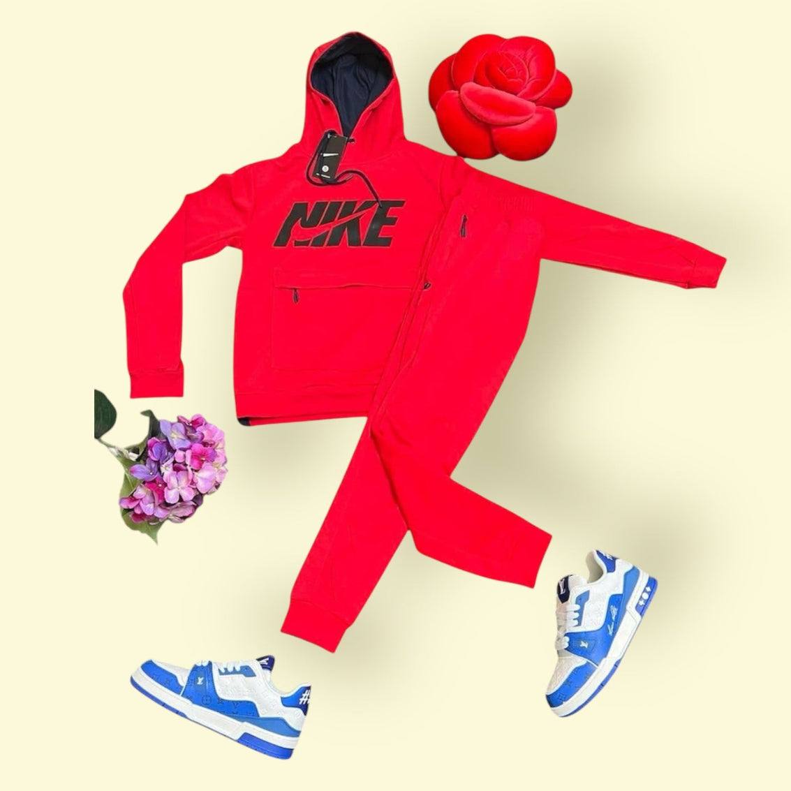 Red Nike tracksuit with black logo paired with blue and white LV trainers on a light background with decorative flowers