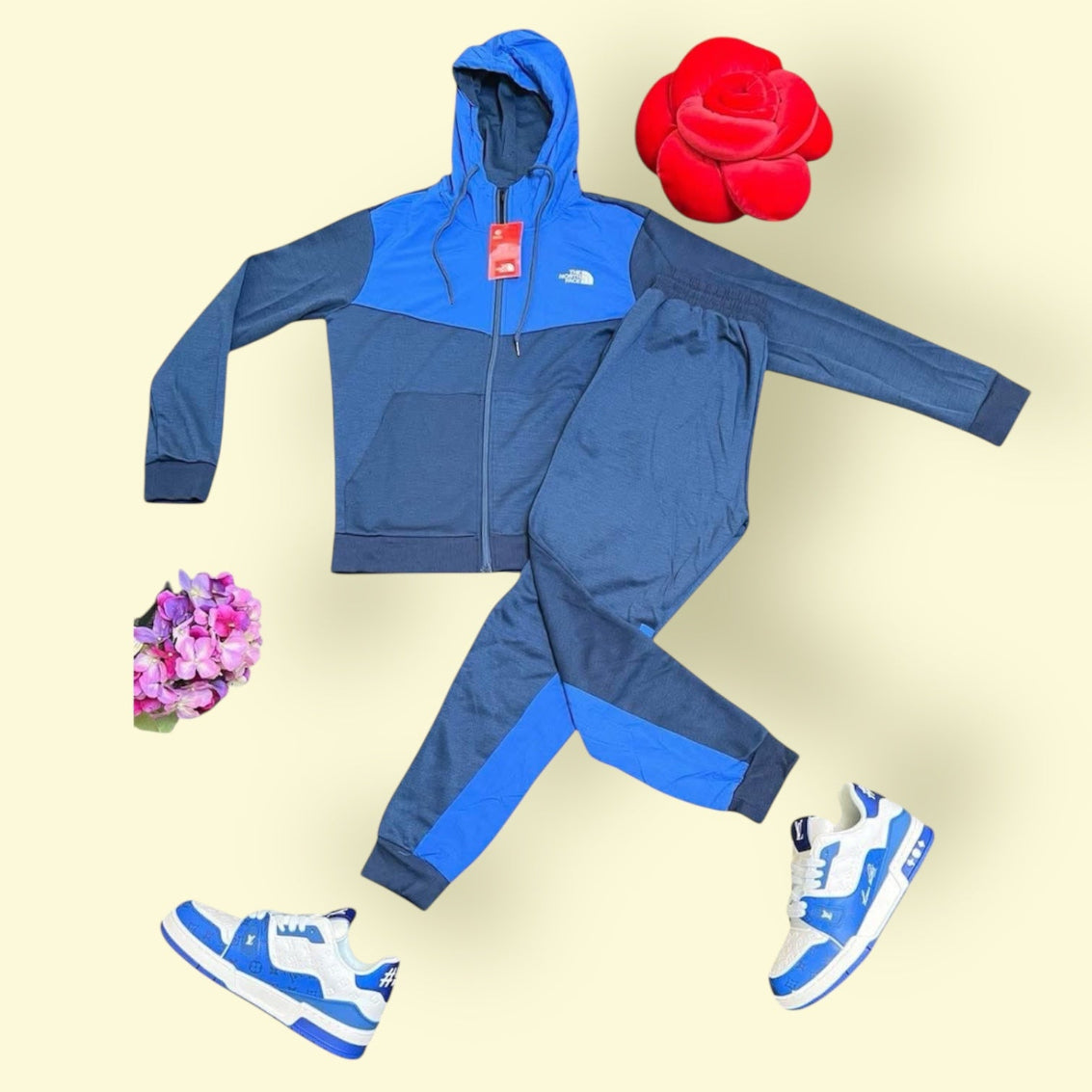 The North Face blue hoodie and tracksuit with matching LV Trainer sneakers bundle on beige background